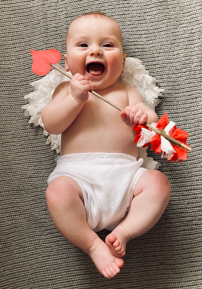 a baby in diapers holding a flower and sticking it's tongue into the air