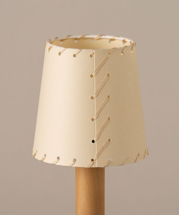 a lamp that is on top of a wooden pole with a white shade over it