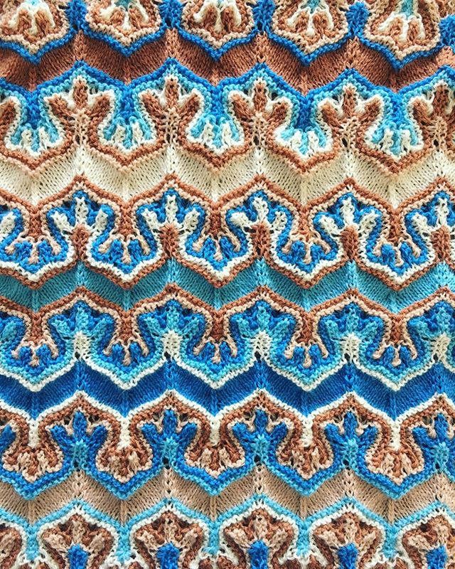 a crocheted blanket with blue, brown and white designs