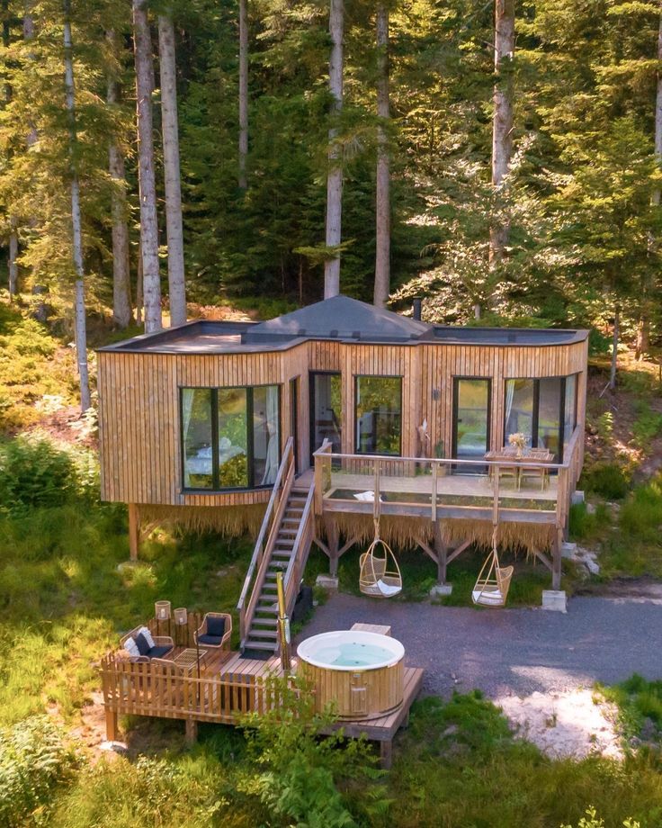 an aerial view of a small cabin in the woods with hot tub and stairs leading up to it