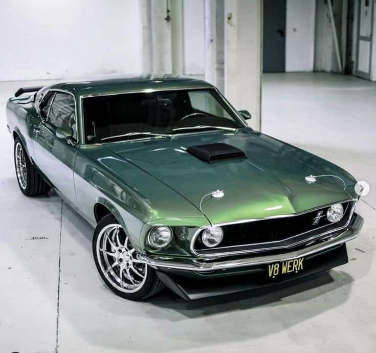 a green muscle car parked in a garage