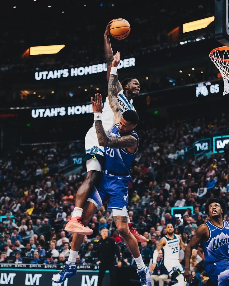 the basketball player is going to dunk the ball in front of the other player