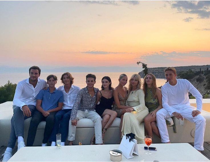 a group of people sitting on top of a couch next to each other near the ocean