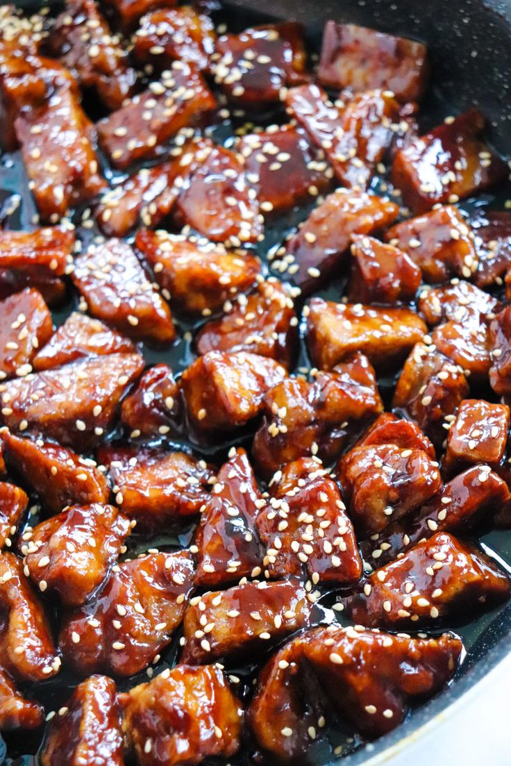 a pan filled with meat covered in sesame seeds