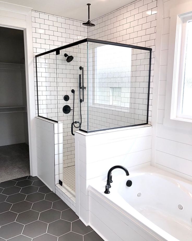 a bathroom with a tub, shower and tiled flooring in black and white colors