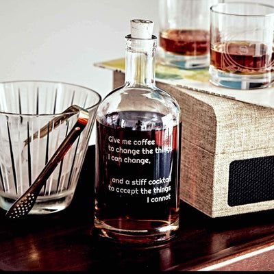 a bottle of alcohol sitting on top of a wooden table next to a glass bowl