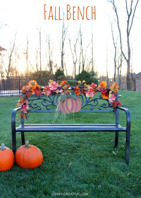 a bench decorated with fall flowers and pumpkins in the grass next to two small pumpkins