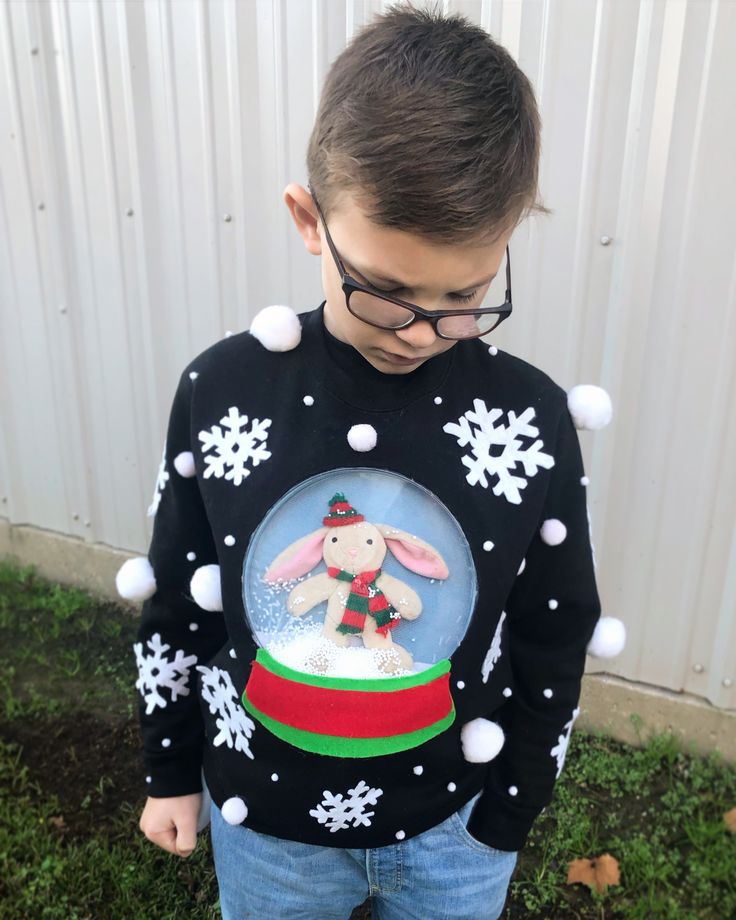 a young boy wearing an ugly sweater with snowflakes and a bunny in it