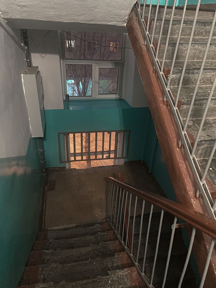 the stairs lead up to an open door in a building with blue walls and white railings