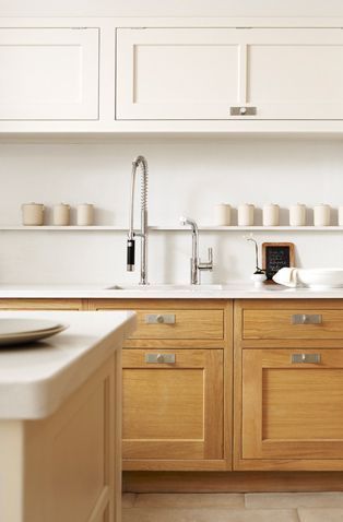 a kitchen with wooden cabinets and white counter tops, along with dishes on the counters