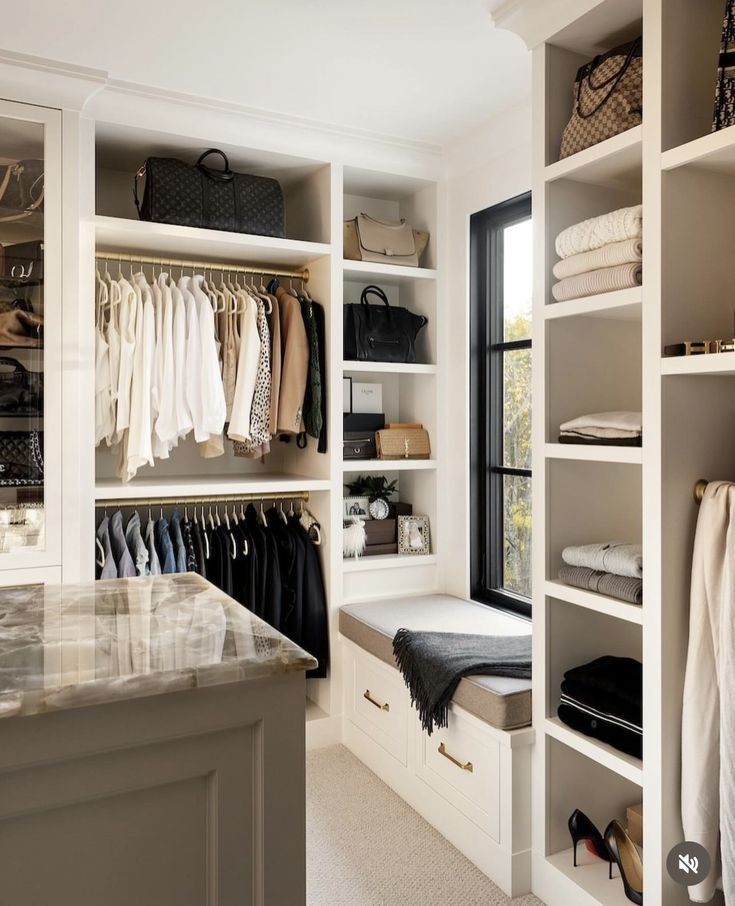 a walk in closet filled with lots of clothes and bags next to an open window