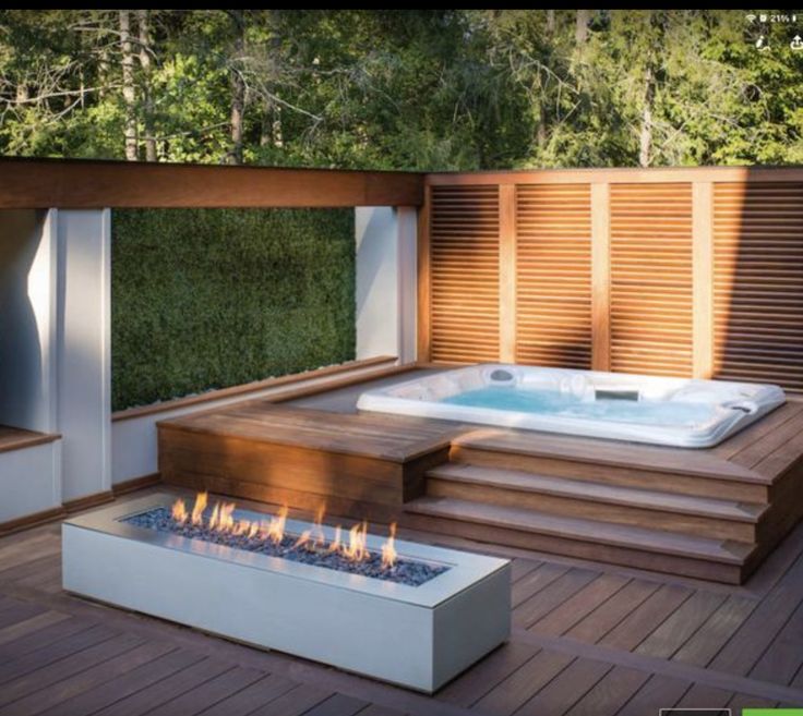 a hot tub sitting on top of a wooden deck next to a fire pit and stairs