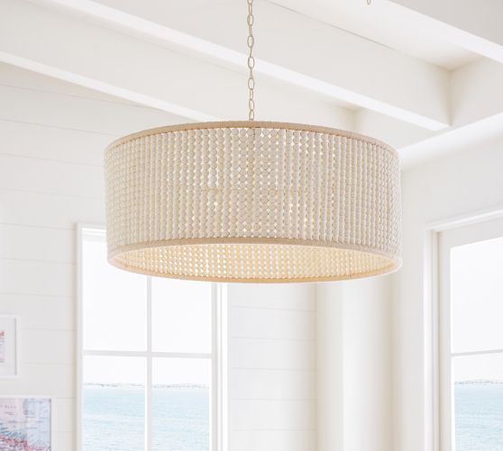 a chandelier hanging from the ceiling in a living room with white walls and windows