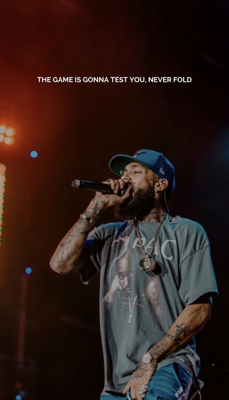 a man with a beard and tattoos on his face singing into a microphone at a concert