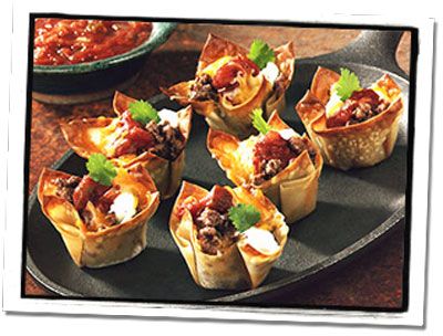 mini taco cups with meat and salsa in them on a black plate, ready to be eaten