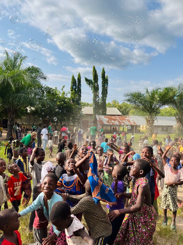 a group of people standing around each other in front of some trees and water bubbles