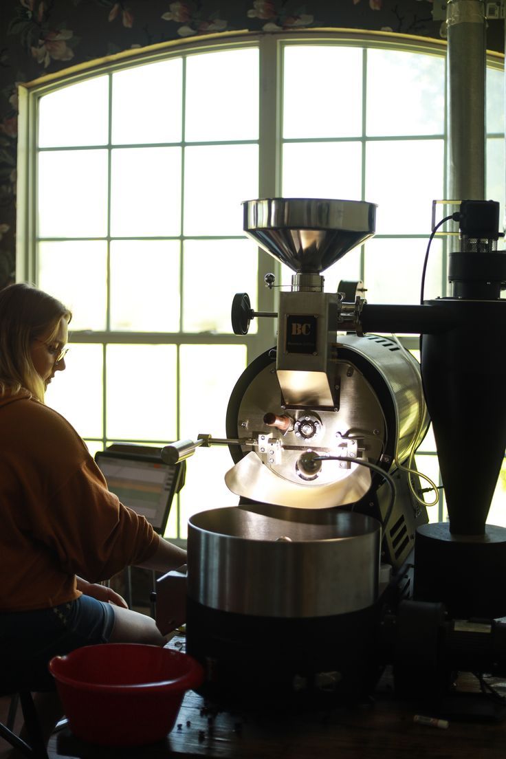 a woman working on a machine in front of a window with sunlight streaming through it