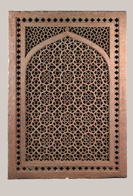 an intricately carved wooden panel in the shape of a door, with geometric designs on it