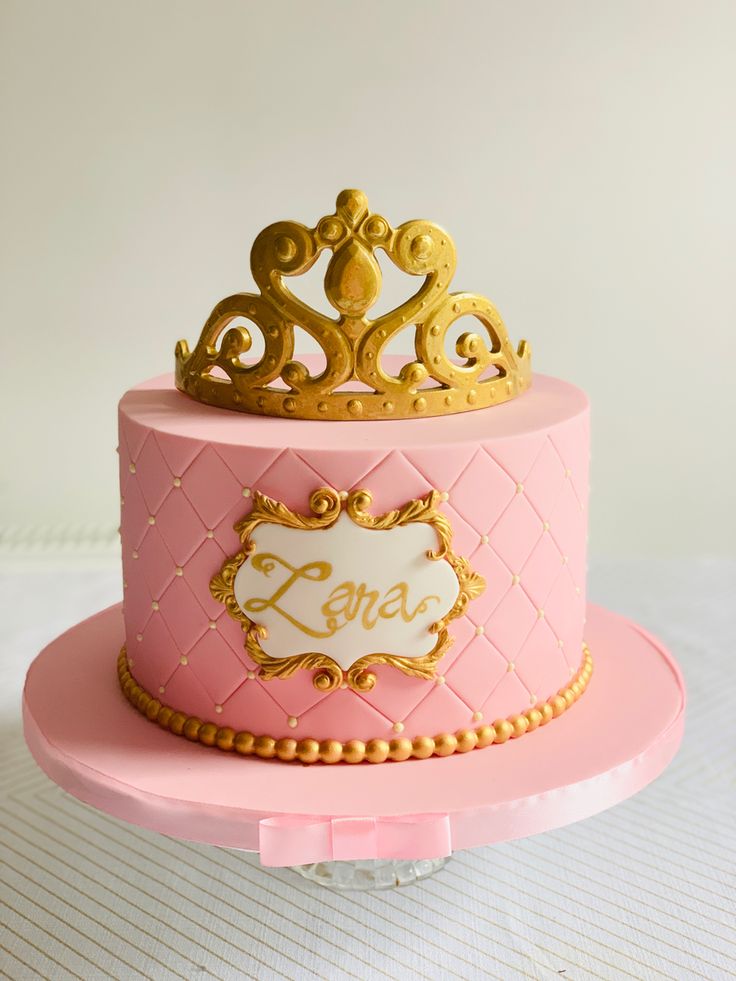 a pink and gold cake with a crown on top