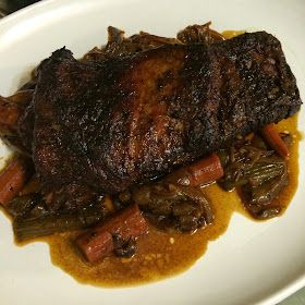 a white plate topped with meat and veggies covered in gravy on top of a table