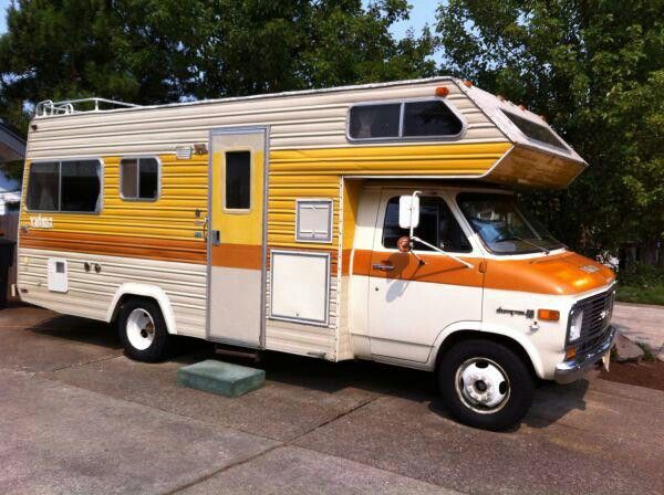 an orange and white camper parked in front of a house