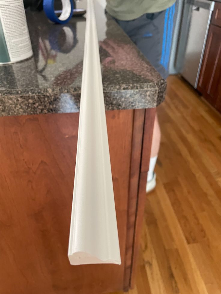 a person standing in a kitchen next to a counter with a white object hanging from it's side