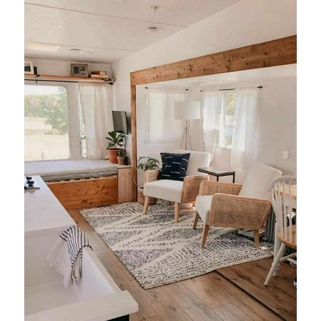 a living room filled with furniture next to a bed and a kitchen counter top under a window