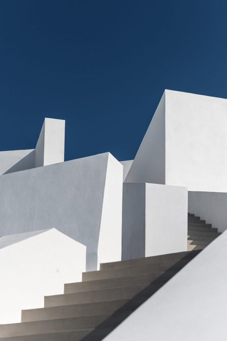 stairs leading up to the top of a white building with blue skies in the background