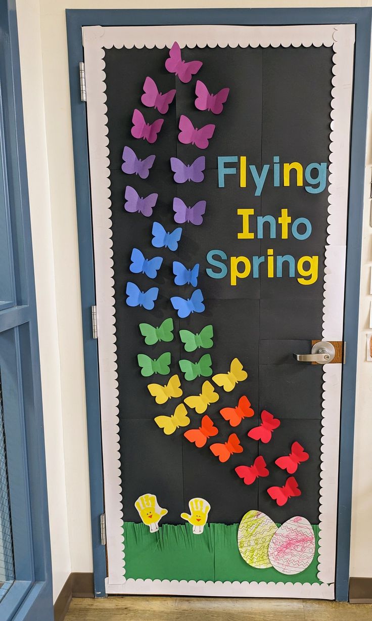 a classroom door decorated with paper butterflies and the words flying into spring written on it