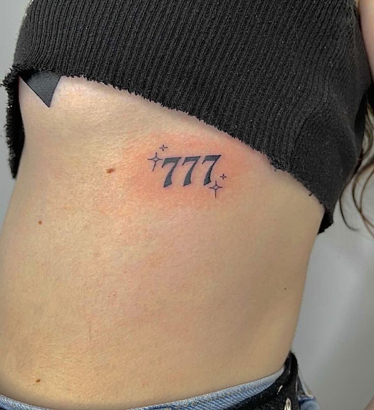 a woman's lower back tattoo with the number seven on her left side ribcage