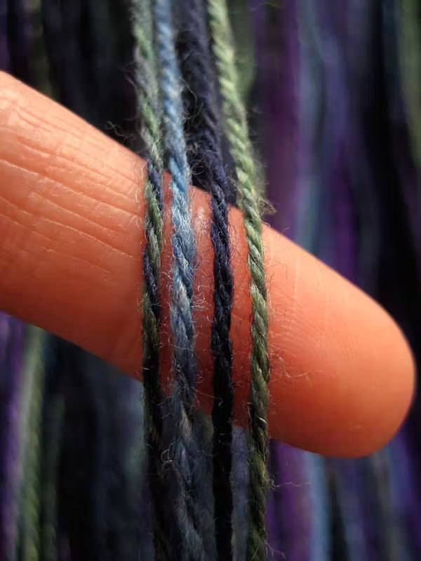 a finger is holding some colorful yarn