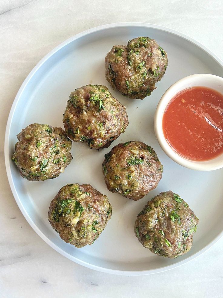 some meatballs are on a plate with ketchup