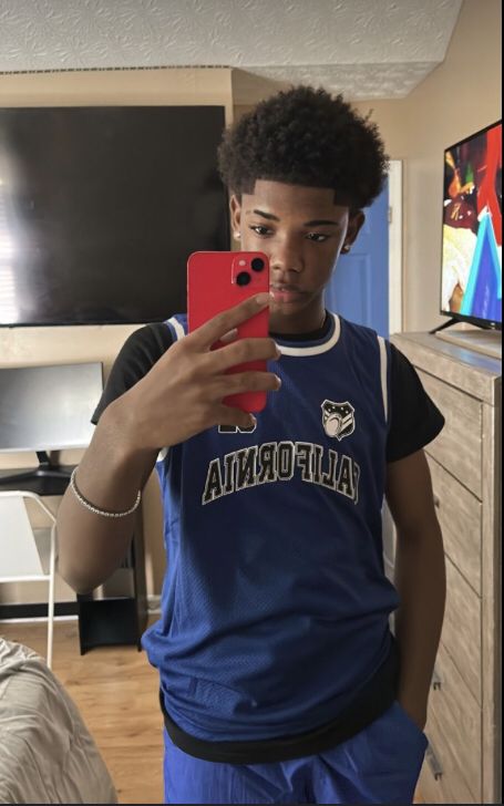 a young man taking a selfie with his cell phone while wearing a blue shirt