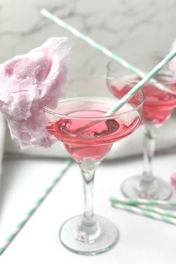 two glasses filled with pink liquid next to cotton swabs and toothbrushes