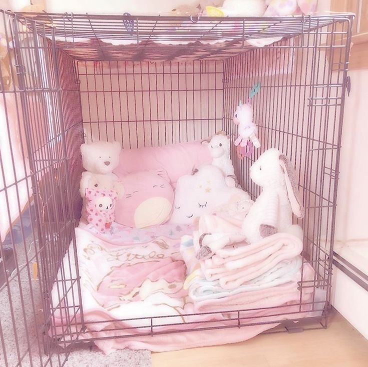 a cage filled with lots of stuffed animals and blankets on top of a wooden floor