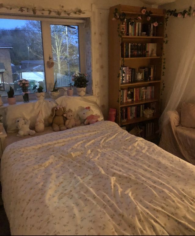 there is a bed with white sheets and teddy bears on it in front of a window