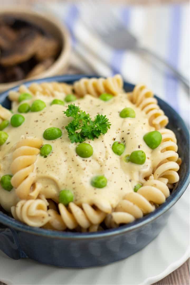 a blue bowl filled with pasta and peas