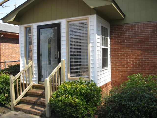 a small house with stairs leading up to the front door