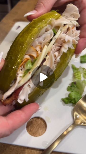 two hands holding a half eaten sandwich on top of a white plate