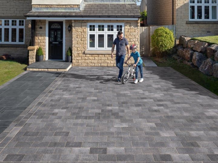 a man and two children are standing in front of a house with a large driveway