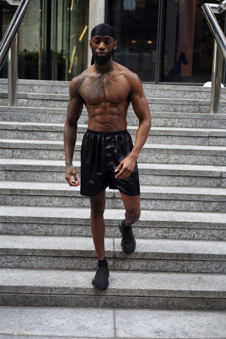 a shirtless man walking down some steps with his hands in his pockets and one hand on his hip