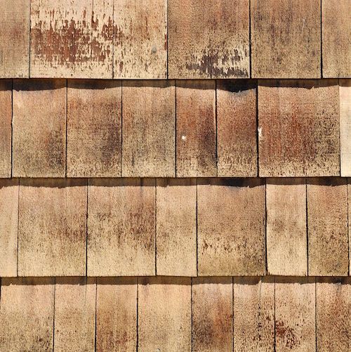 a close up view of a brown roof that has been gutted with wood shingles