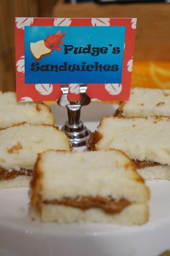 some sandwiches are on a white plate with a red and blue sign that says fudge's sandwiches