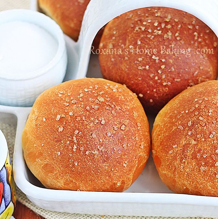 four rolls in a white container with dipping sauce