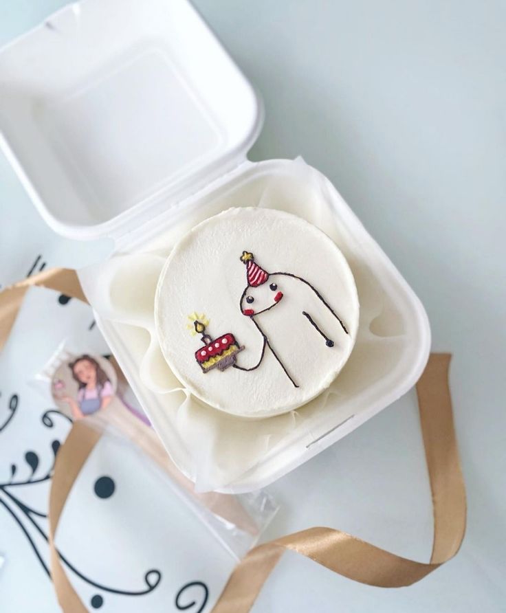 a decorated cookie in a plastic container with a brown ribbon around it and an image of a unicorn on the front