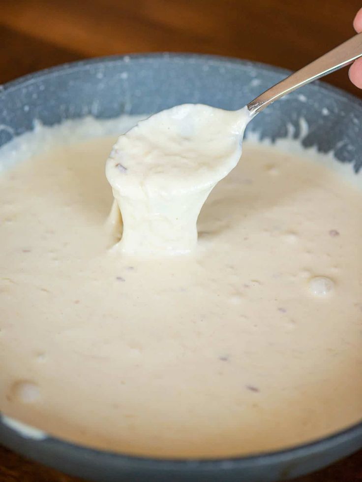 a person holding a spoon full of cream in a bowl