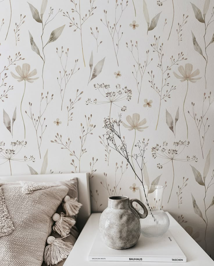 a vase sitting on top of a white table next to a wallpapered wall