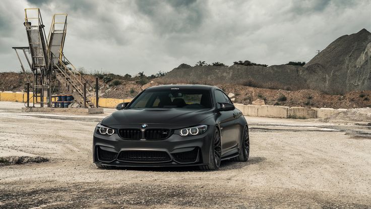 a black car parked in the middle of a dirt road