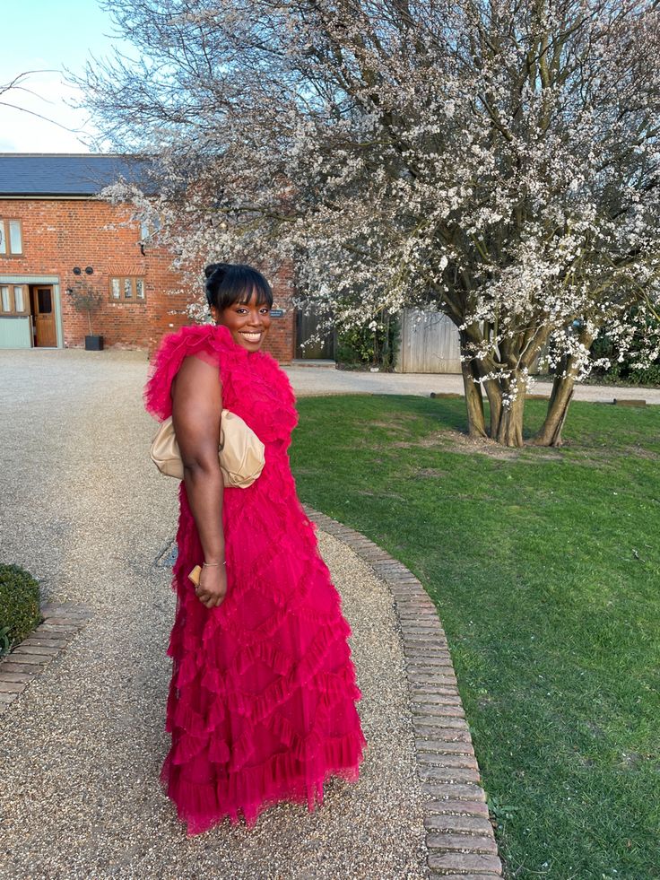 a woman in a red dress standing on the sidewalk