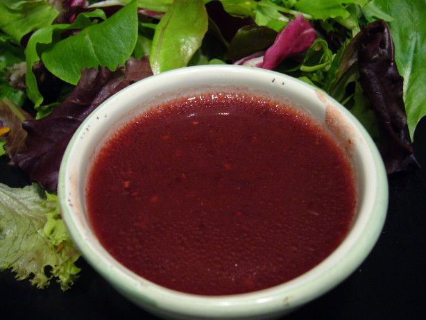 a white bowl filled with red liquid sitting on top of a pile of lettuce